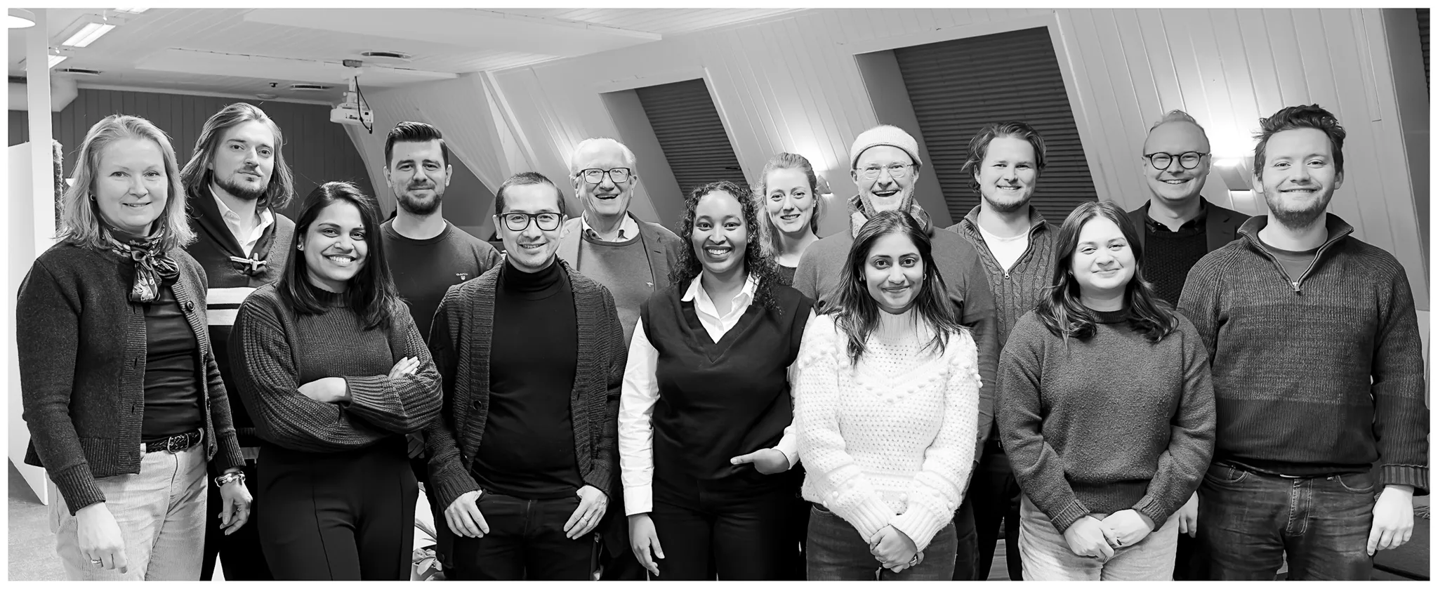 AboutUsHeroFin Group photo of the syntrix data Software team standing together in an office setting, smiling and facing the camera.